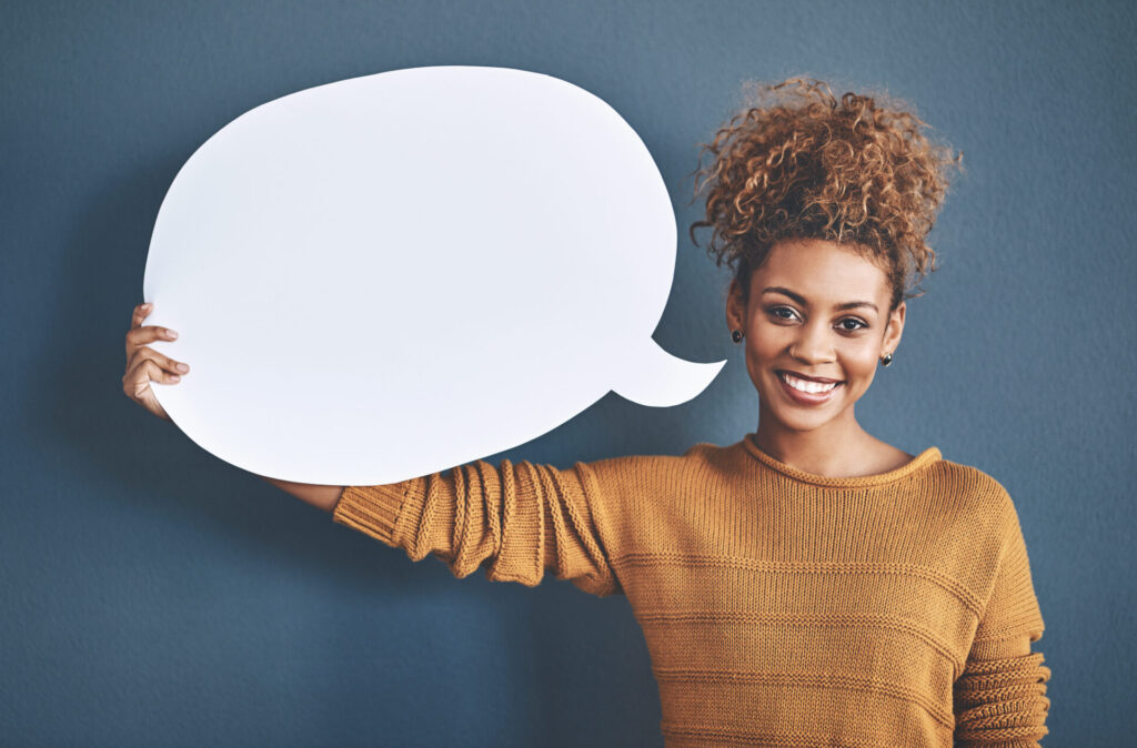 Studio shot of a young woman holding a speech bubble against a grey background
